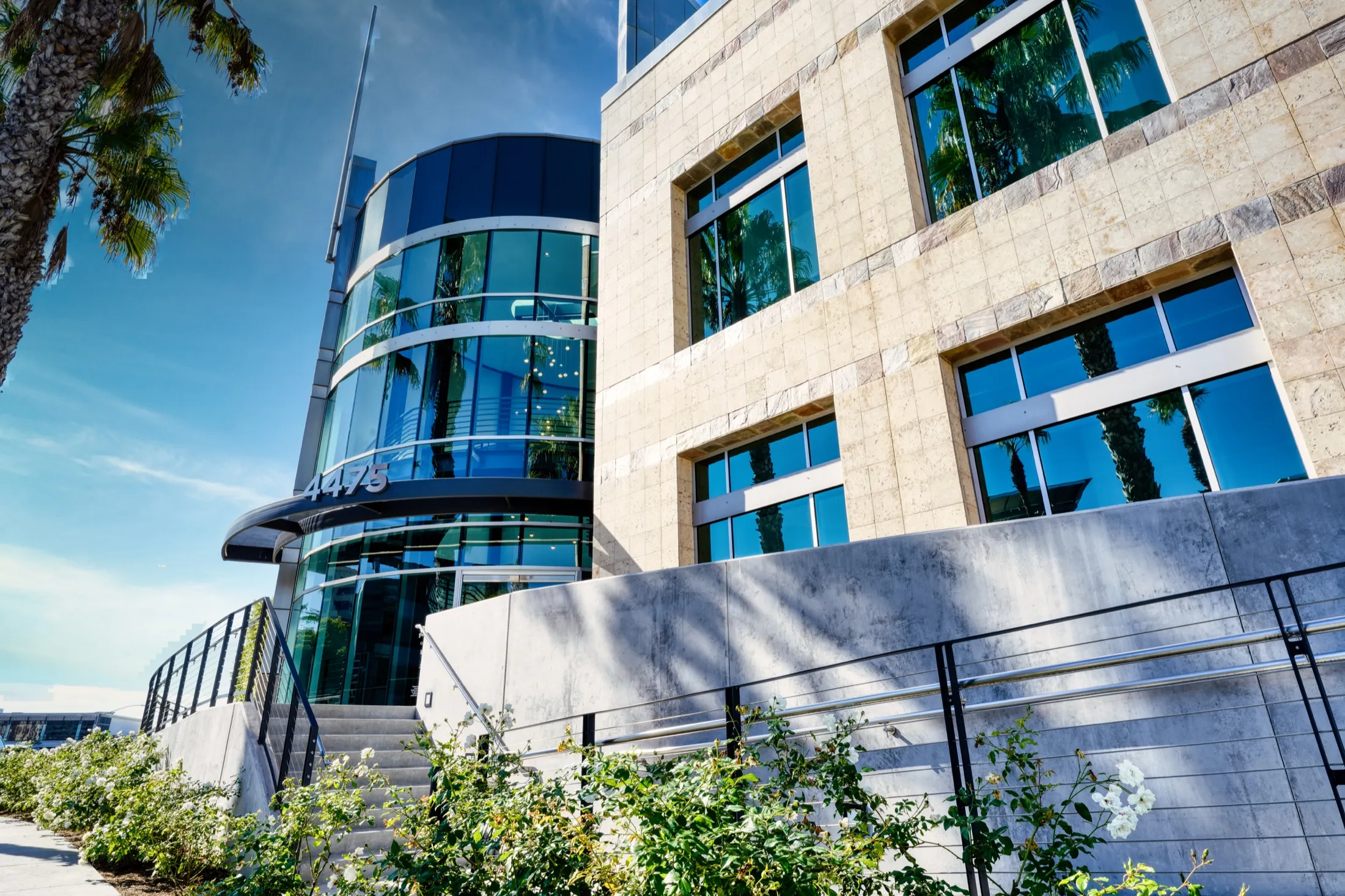 Glass entry tower and stone facade of 4475 Executive Drive, San Diego, from the front walk