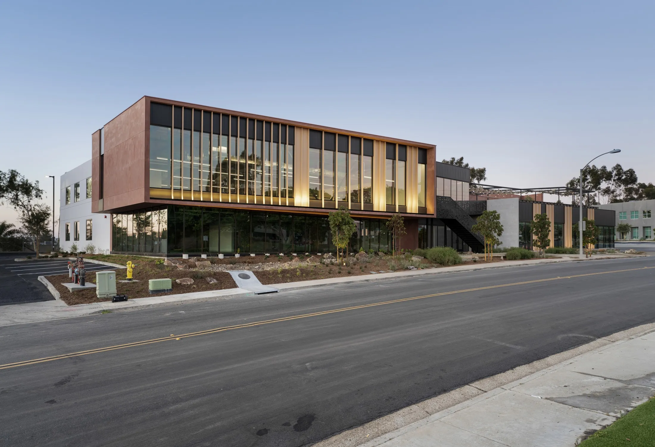 Street-level dusk view of 6610 Nancy Ridge's glass and wood-fin facade