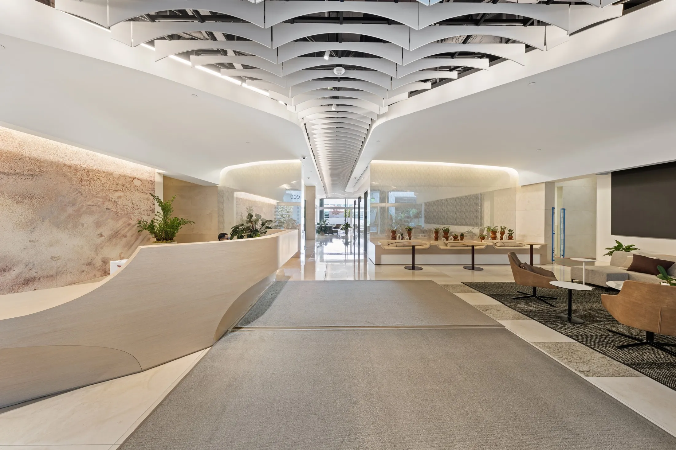 909's lobby, marble floors, a sculpted reception desk and a rippled white ceiling