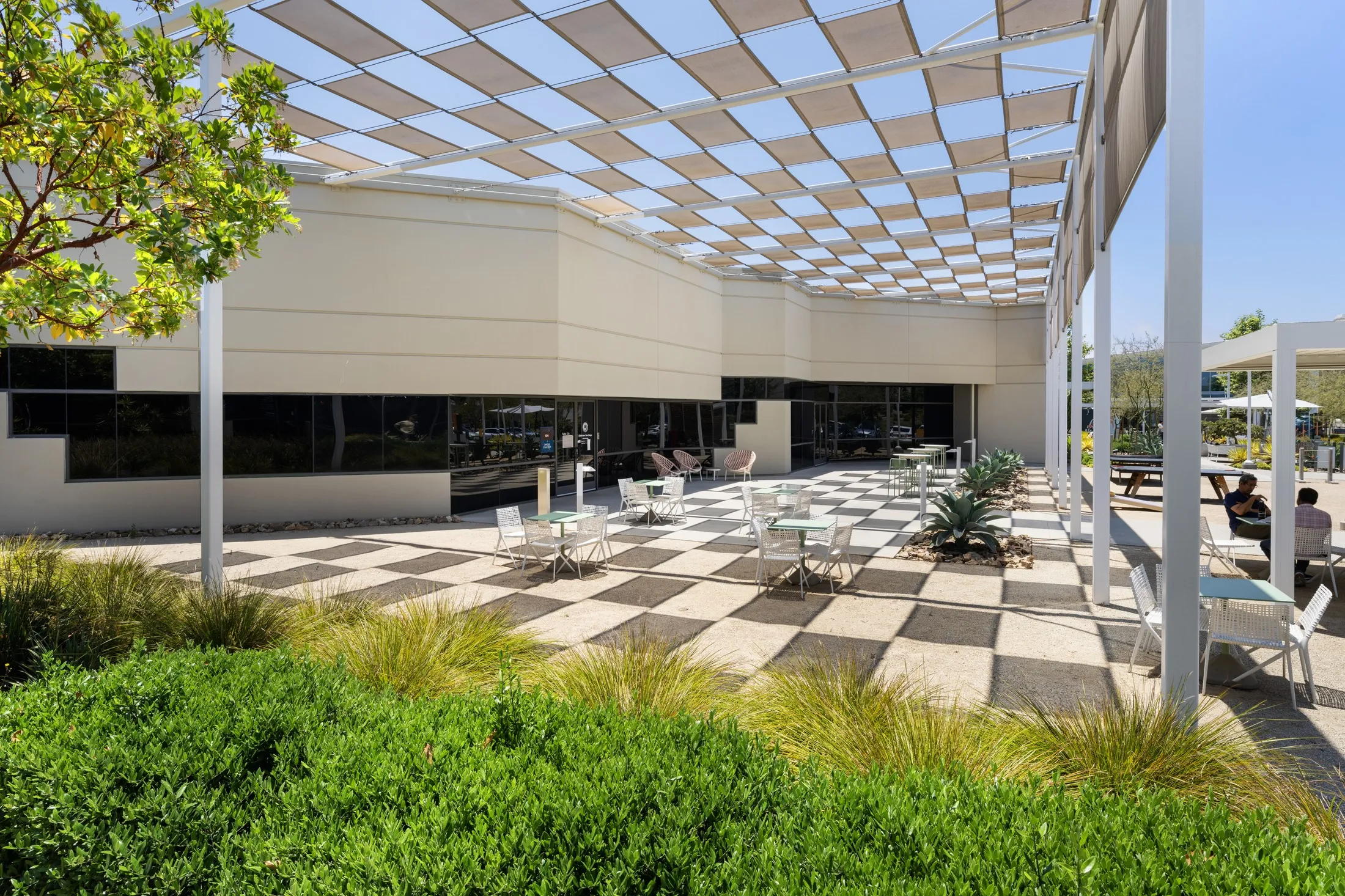 Checkerboard-paved courtyard with café seating between buildings